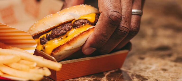 African American man with wedding ring taking a burger from a box, fast food