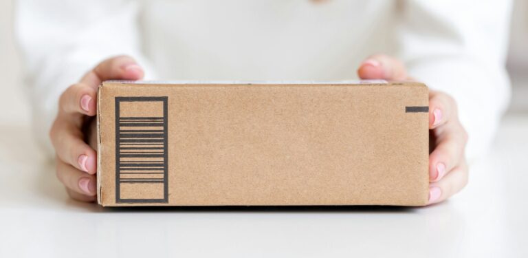 Woman holding in hands delivered goods in cardboard box. Mock-up friendly design with copy space.